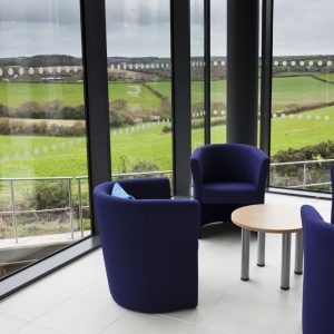 HWIC atrium, chairs around a coffee table, and open countryside behind